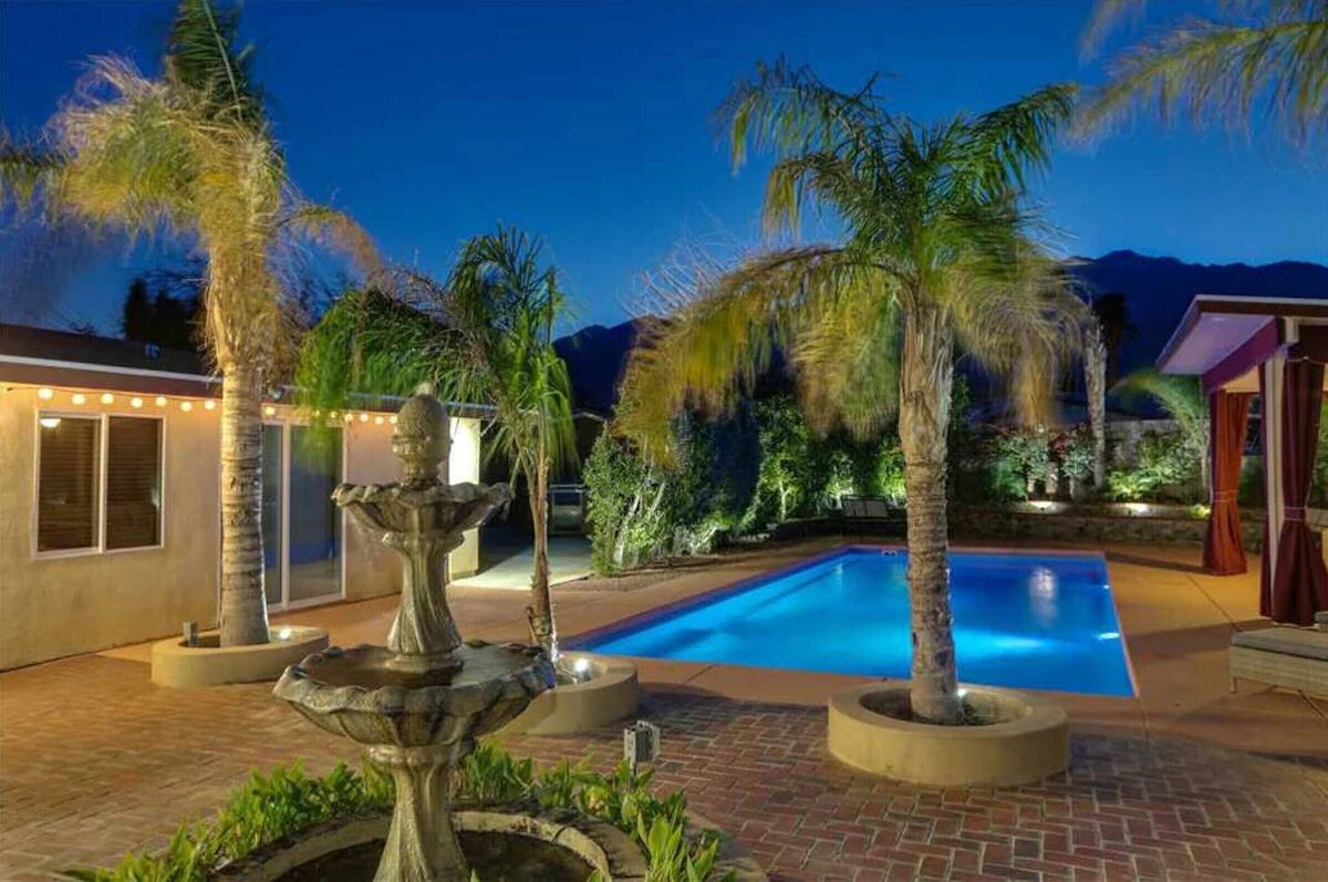 Palm Springs pool with fountain and mountain backdrop at night